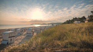 Une plage bordée de rangées de chaises de plage blanches, avec une zone herbeuse au premier plan.