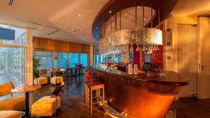 Un espace bar doté d’un comptoir incurvé, de sièges confortables et d’une grande fenêtre offrant une vue panoramique.