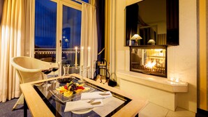 Un coin repas avec une table dressée pour deux personnes, une cheminée et une vue sur le ciel nocturne grâce à de grandes fenêtres.