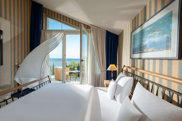 Habitación de hotel con una cama grande, un balcón con vistas y un cuadro en la pared.