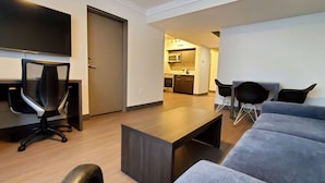 A modern living room with a sofa, a coffee table, a TV, and a desk with a chair. - Super 8 by Wyndham Macleod Trail Calgary (Calgary)