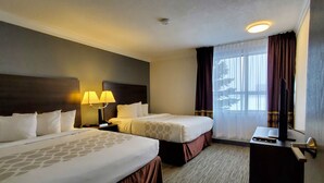 A hotel room with two beds, a desk with a computer and remote, a window with curtains, and a ceiling light. - Super 8 by Wyndham Macleod Trail Calgary (Calgary)