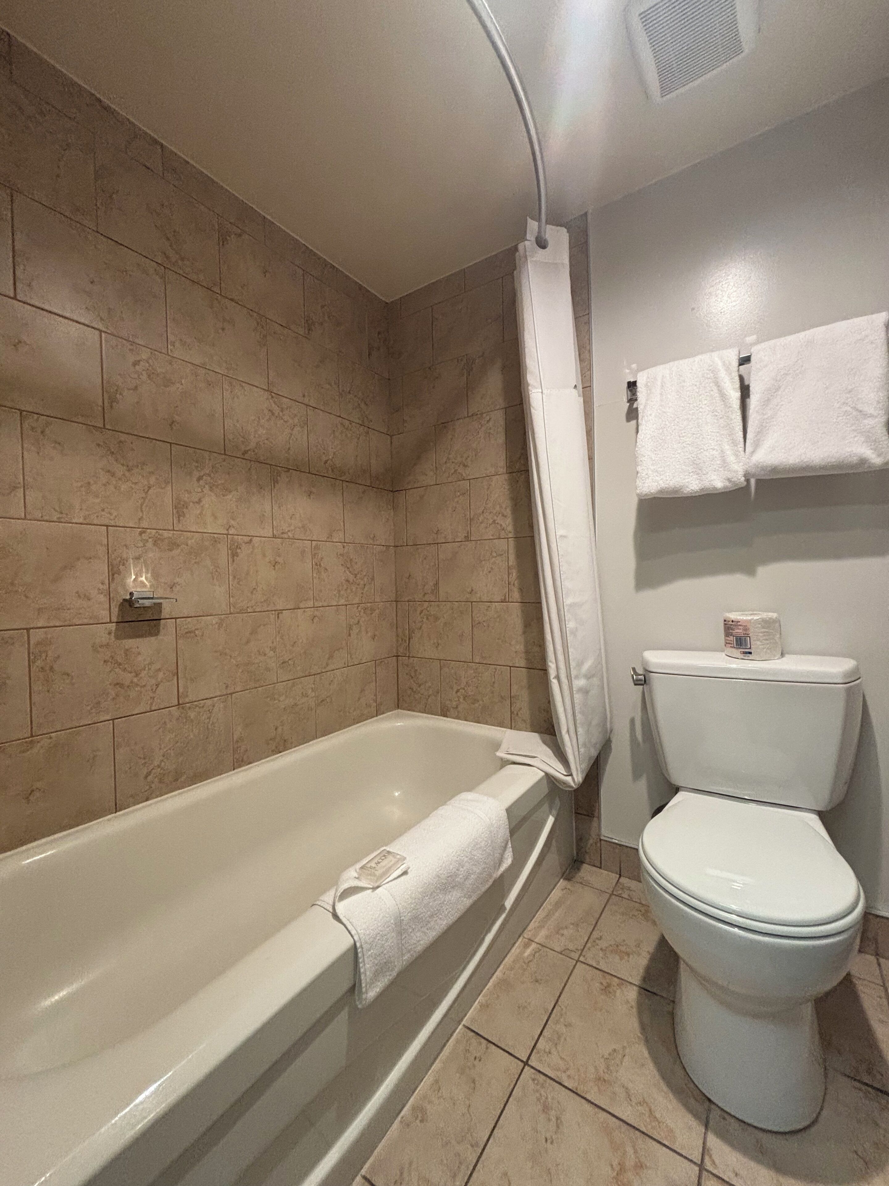 Un baño con bañera, inodoro y cortina de ducha.