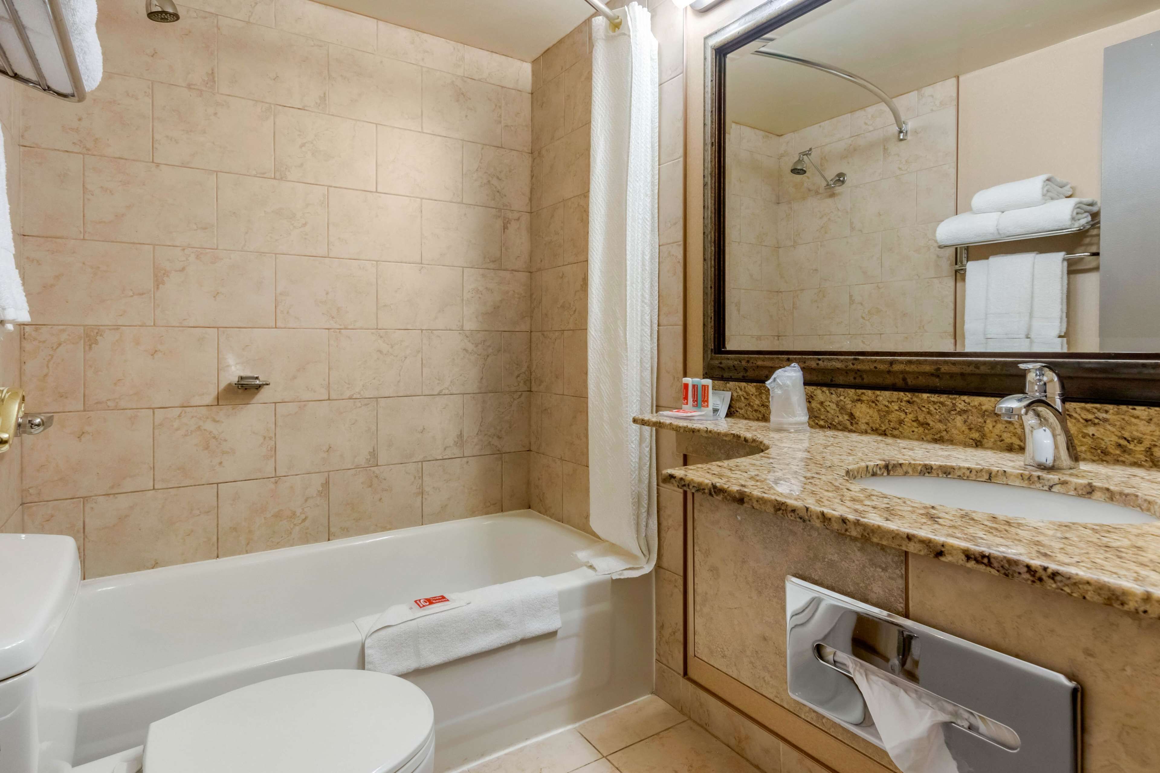 Un baño con bañera, inodoro, lavabo y espejo.