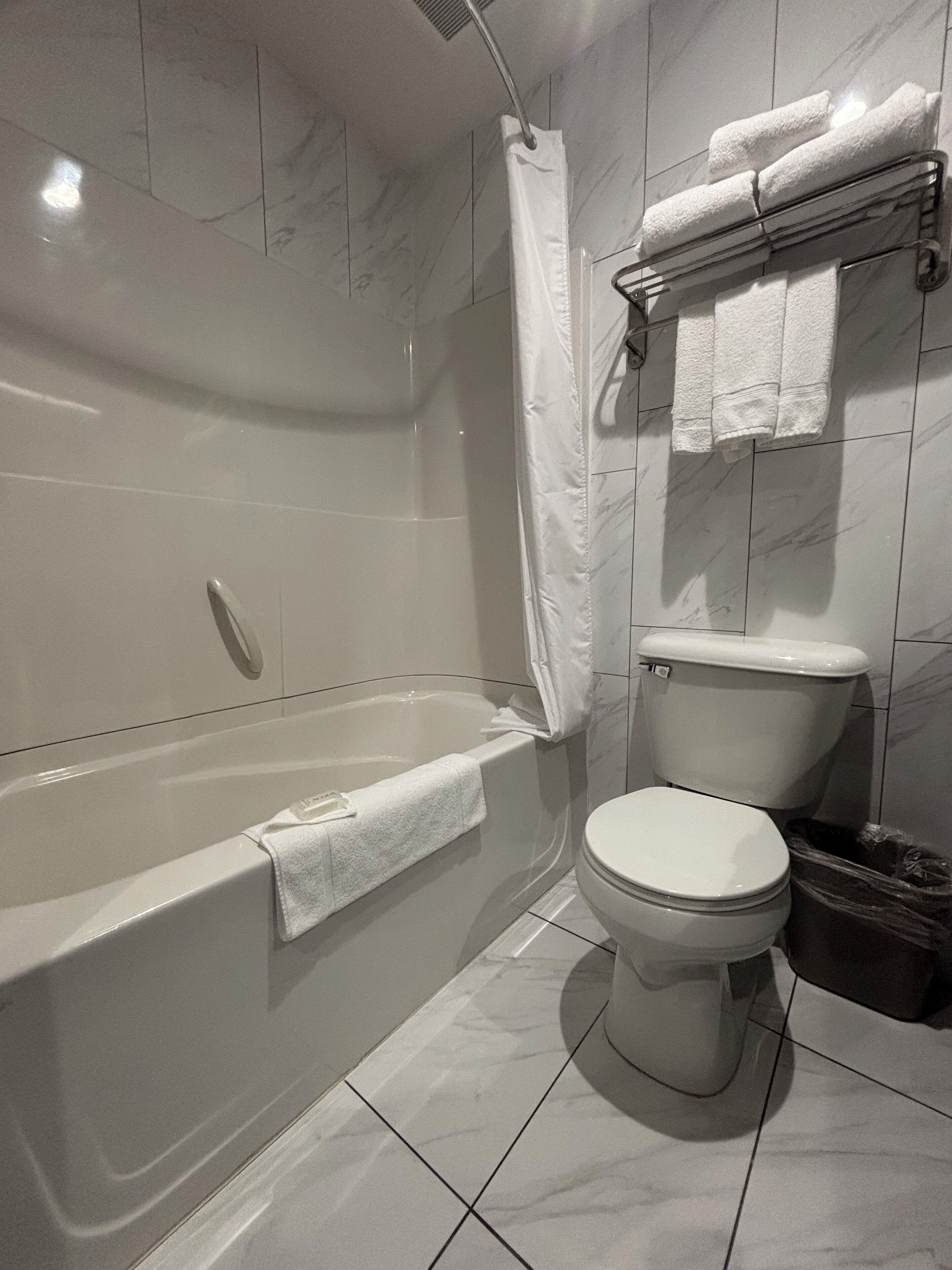 A modern bathroom with a bathtub, toilet, and a shower curtain.