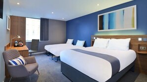 A modern hotel room with two beds, a seating area, and a large window. - Travelodge London Docklands (London)