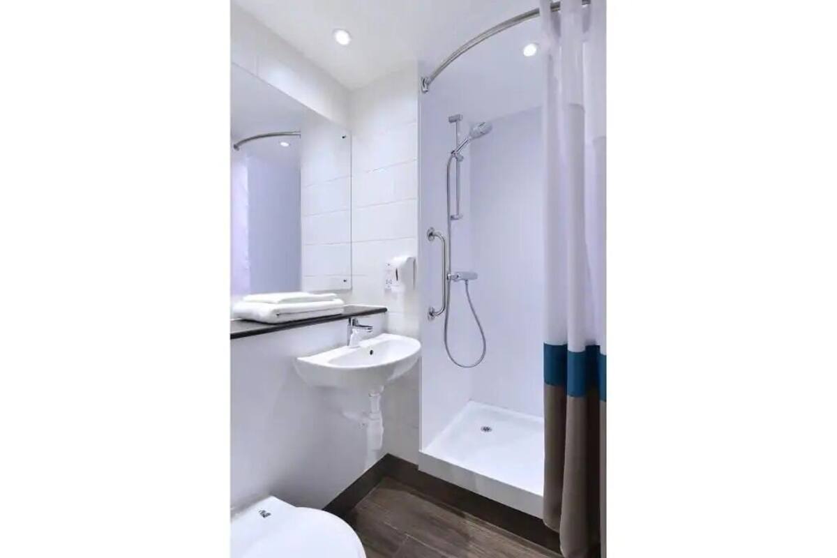 A modern bathroom with a shower, sink, and toilet.