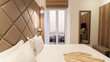 Een hotelkamer met een groot bed, een houten hoofdeinde, een balkon met tuinmeubilair en een spiegel aan de muur.