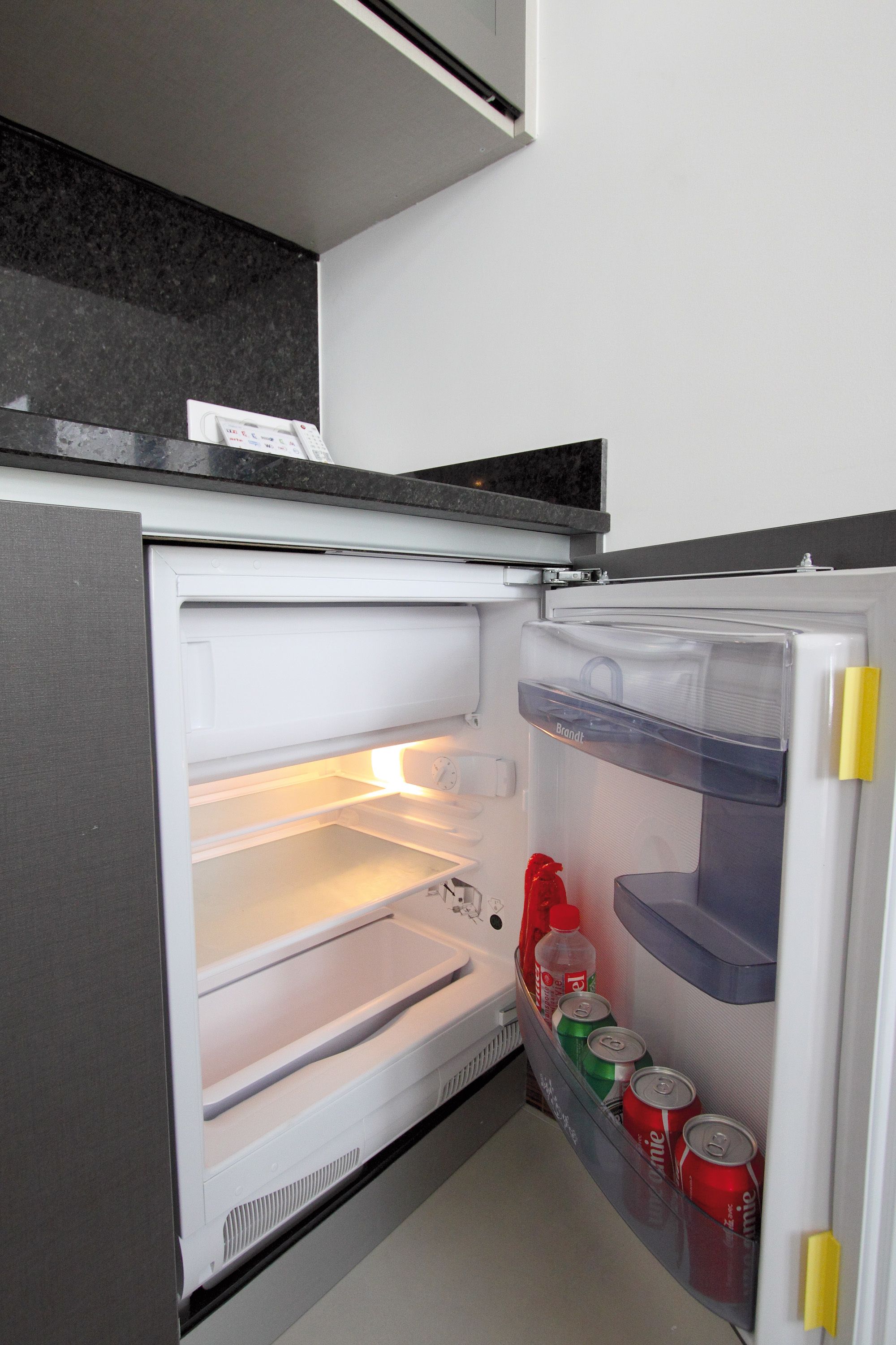 A refrigerator with a freezer compartment, a water dispenser, and a shelf with beverages.
