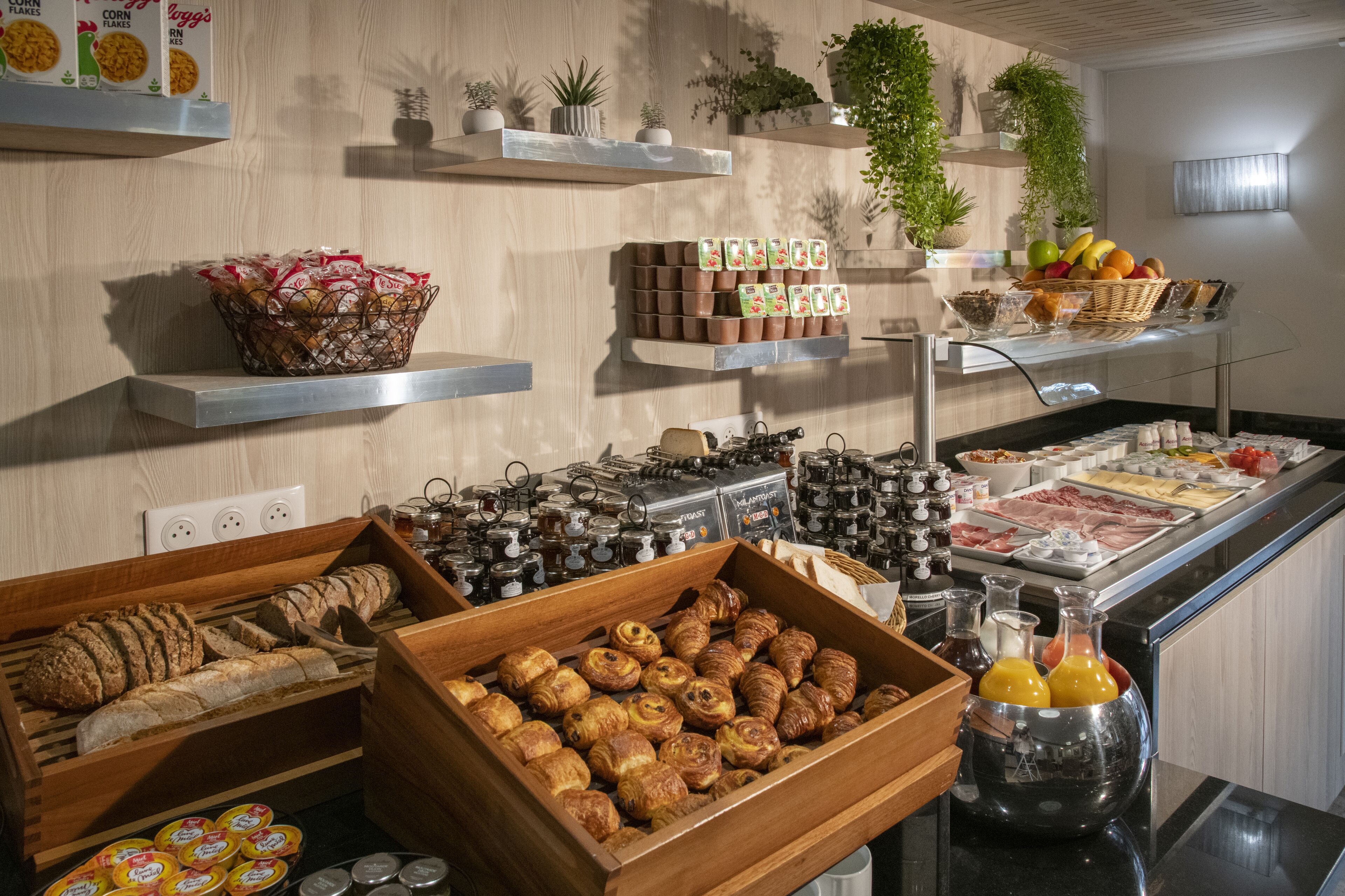 A breakfast buffet with various food items, including bread, pastries, and fruits.