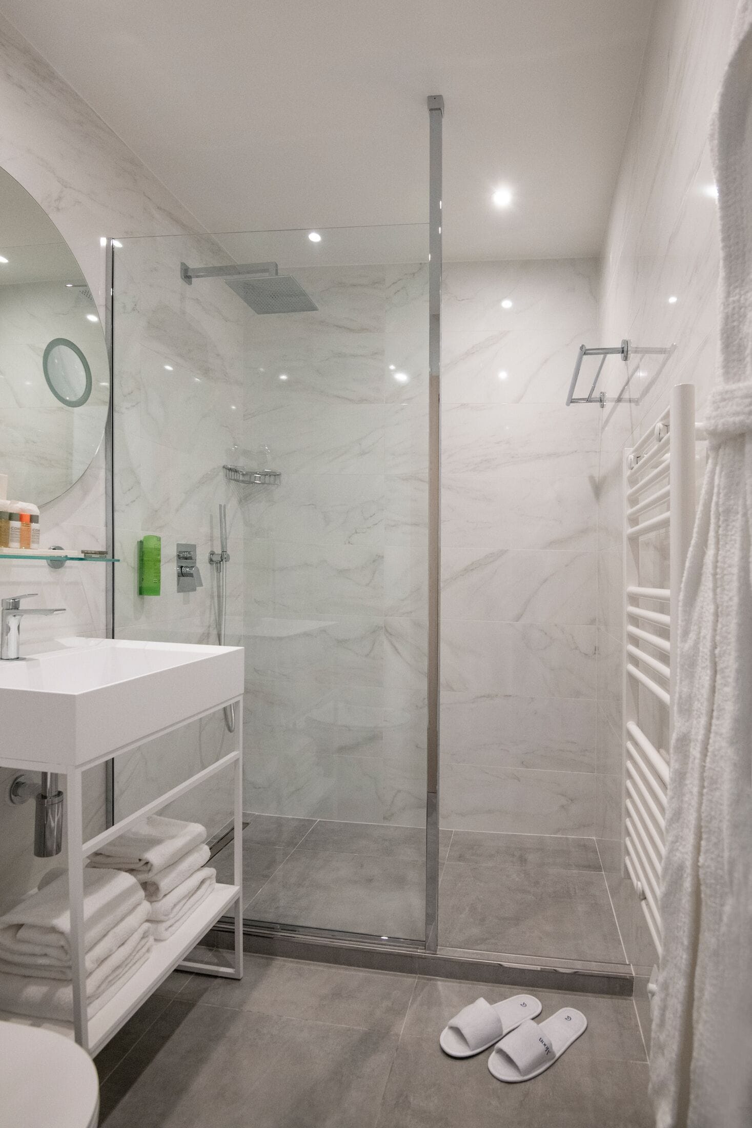 Une salle de bain moderne avec une douche à parois de verre, un lavabo blanc et un porte-serviettes.