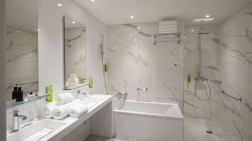 A modern bathroom with a large mirror, two sinks, a bathtub, and a shower.