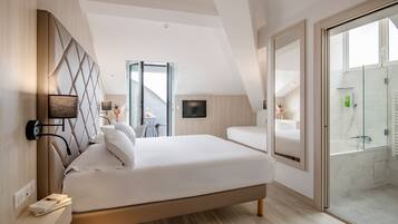 Une chambre à coucher moderne avec un grand lit, un téléviseur fixé au mur et une douche en verre.