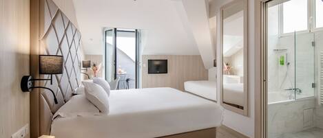 Une chambre à coucher moderne avec un grand lit, un téléviseur fixé au mur et une douche en verre.