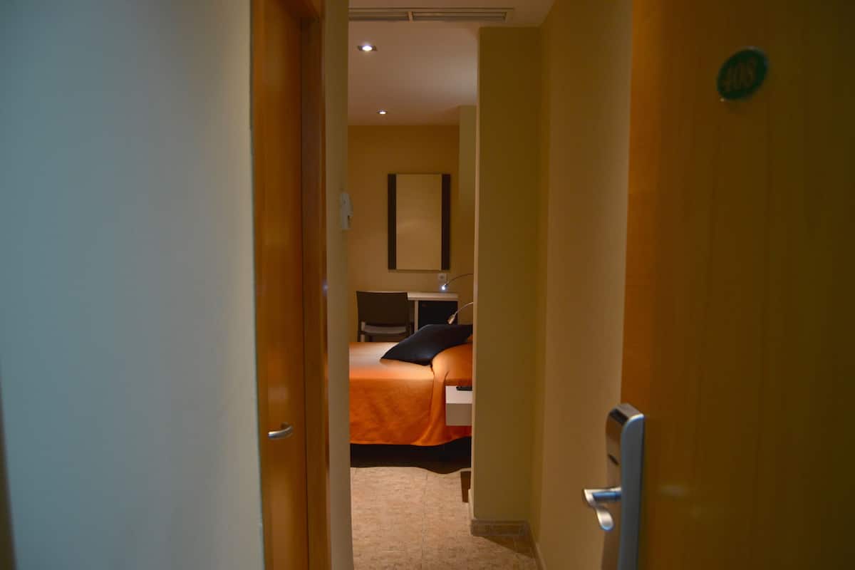 Una habitación de hotel con una cama, un escritorio y una silla.