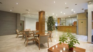 Un vestíbulo amplio con mostrador de recepción, zona de estar y una gran planta de interior.