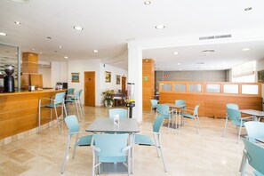 A modern hotel lobby with a reception desk, seating area, and a dining section. - Hotel Abelux (Palma de Mallorca)