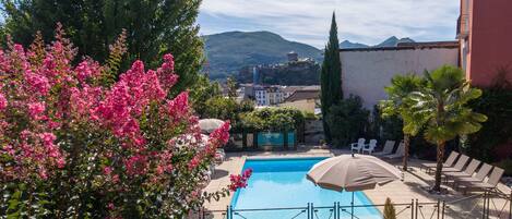 A swimming pool with lounge chairs and a view of a mountain.