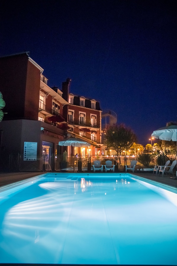 Una piscina al aire libre de temporada, sombrillas, tumbonas