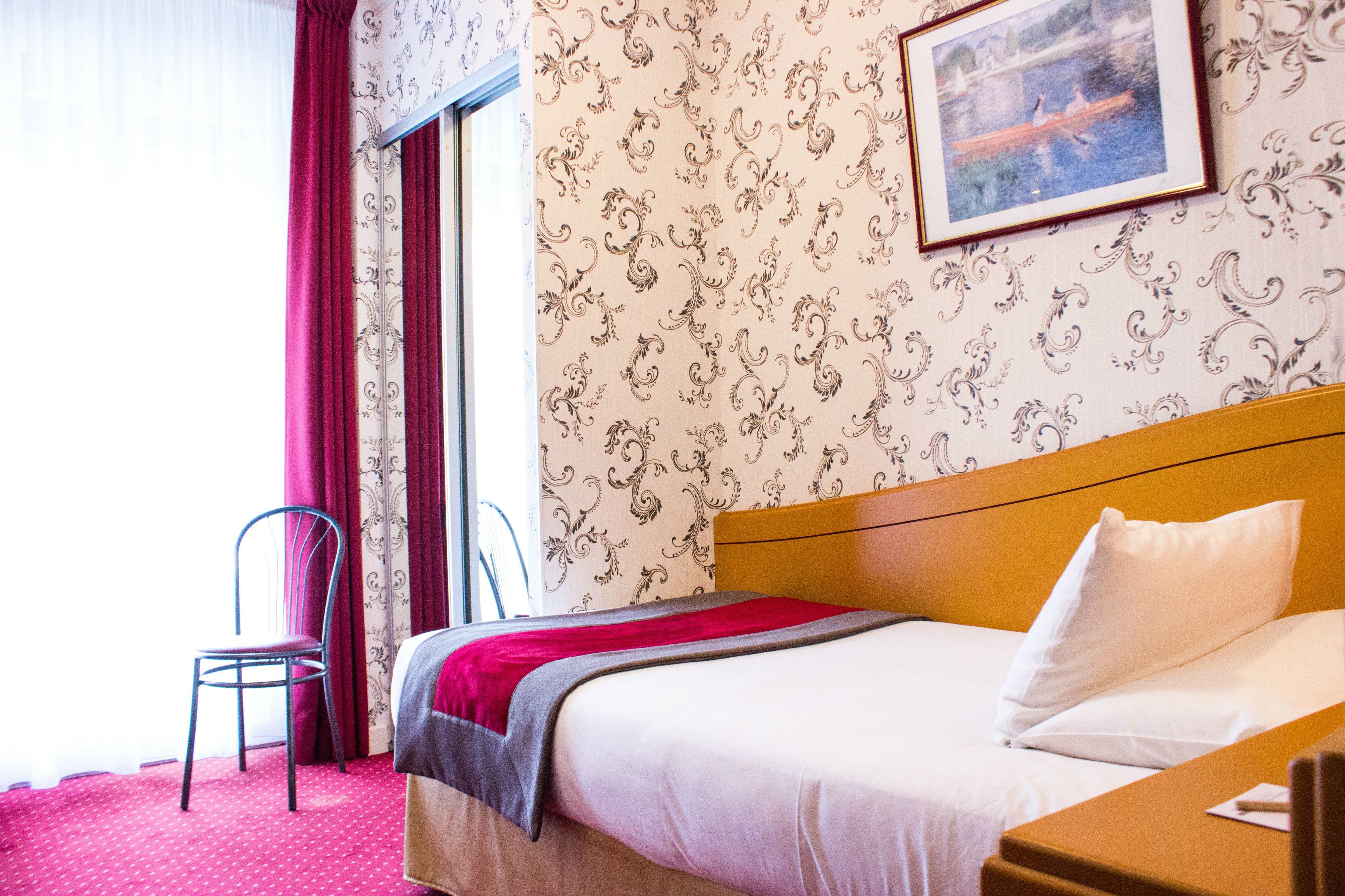 Une chambre d’hôtel avec un lit, une chaise, une fenêtre avec des rideaux et un mur orné d’un tableau encadré.