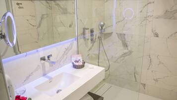 A bathroom with a white sink, a mirror, and a shower area.