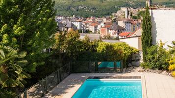 A rectangular swimming pool with a view of a town and mountains in the background.