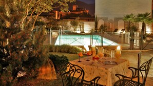 Un área de comedor al aire libre con una mesa dispuesta para dos personas, con vista a una piscina.