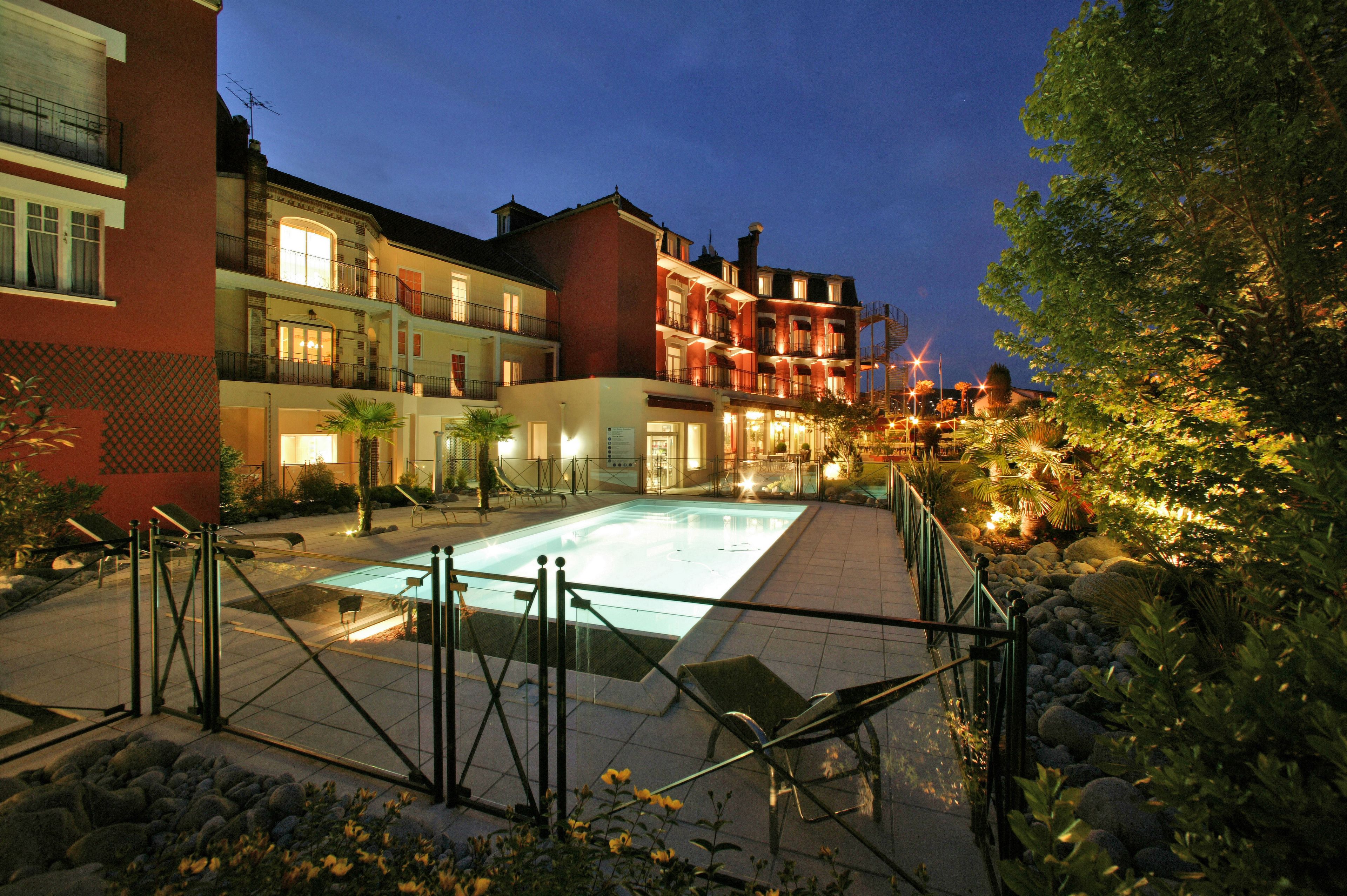 Un patio con piscina, rodeado de edificios con balcones y una entrada bien iluminada.