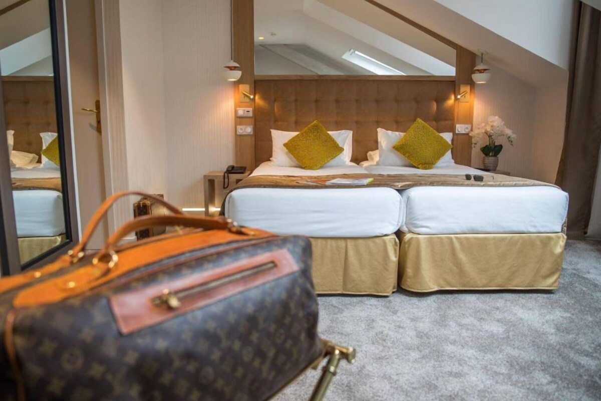 A hotel room with a large bed, a nightstand, a lamp, and a suitcase on the floor.