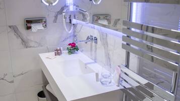 Un baño moderno con un lavamanos blanco, dos espejos redondos, un perchero y un revestimiento de mármol.