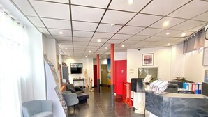 Un'accoglienza moderna con scrivania della reception, angolo salotto e pavimento piastrellato.