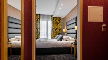Ein Hotelzimmer mit zwei Betten, einem großen Fenster mit Vorhängen und einer Wand mit floralem Muster.