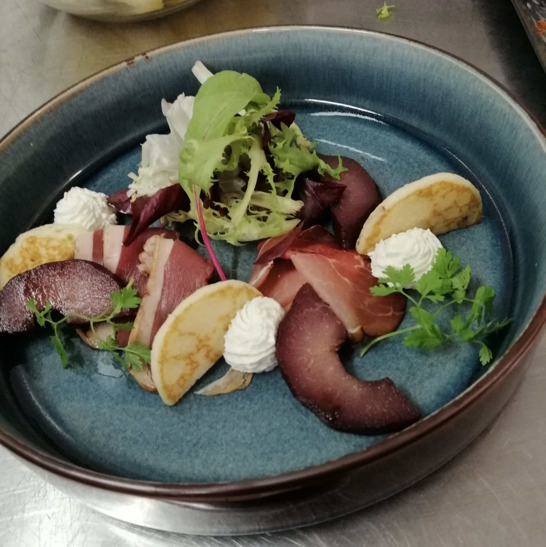 Un plato con diferentes alimentos, incluyendo carne, queso y vegetales.