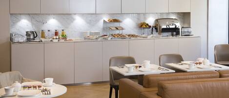 A modern breakfast area with a marble backsplash, buffet with various food items, and seating arrangements.