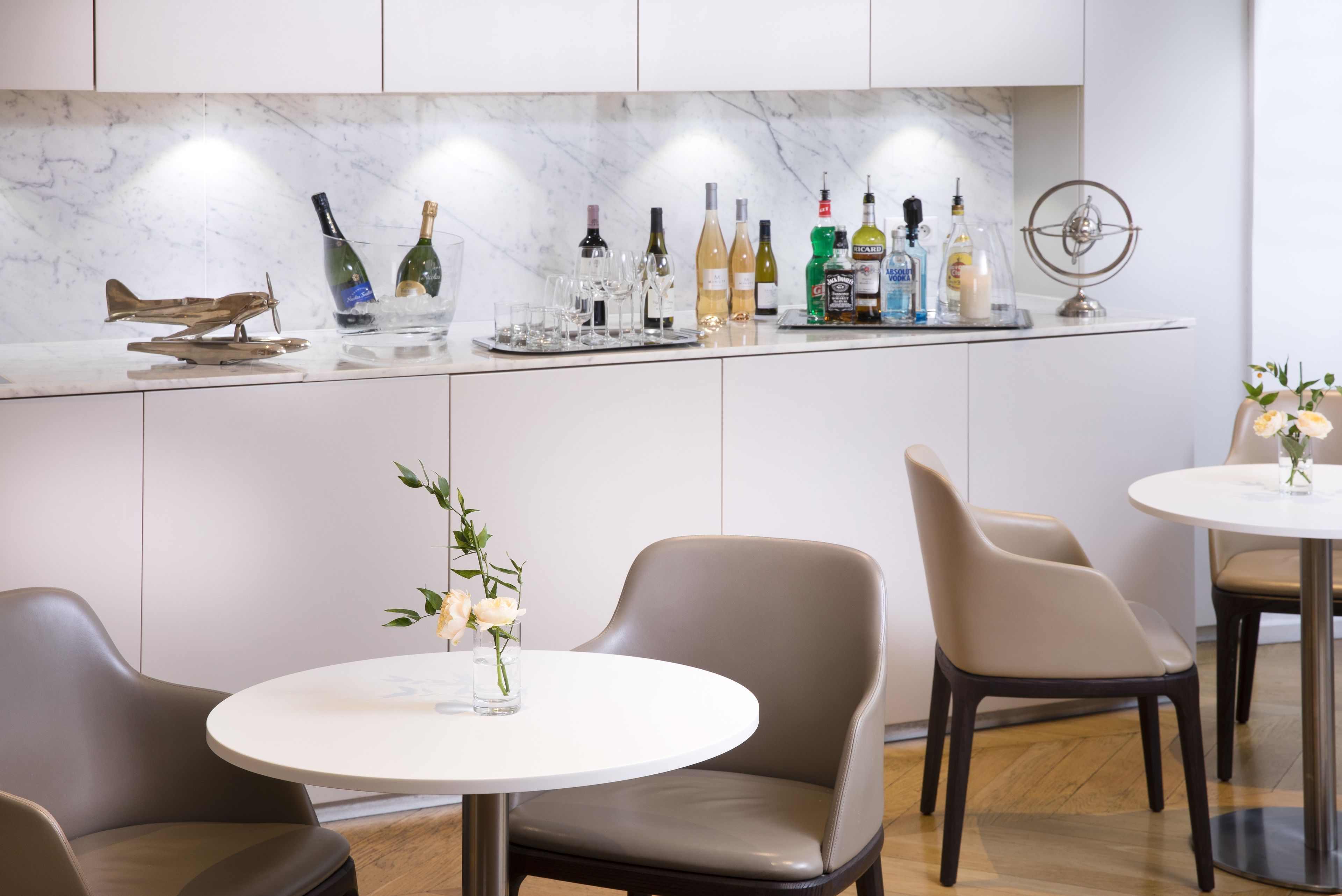 Une cuisine moderne avec un plan de travail en marbre, diverses bouteilles et une maquette d’avion décorative.