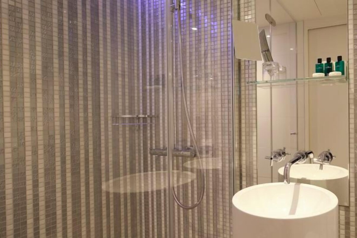 Une salle de bain moderne avec une douche à parois de verre, un grand lavabo et un miroir.