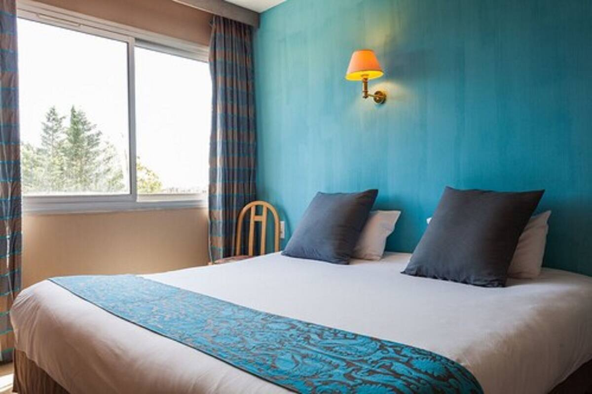 Un dormitorio con una cama grande, una ventana con cortinas y una lámpara de pared.