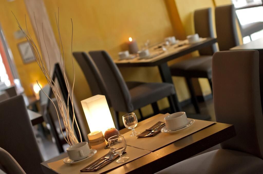 Une table à manger dressée avec une bougie, un vase contenant des plantes séchées, une tasse et une soucoupe.