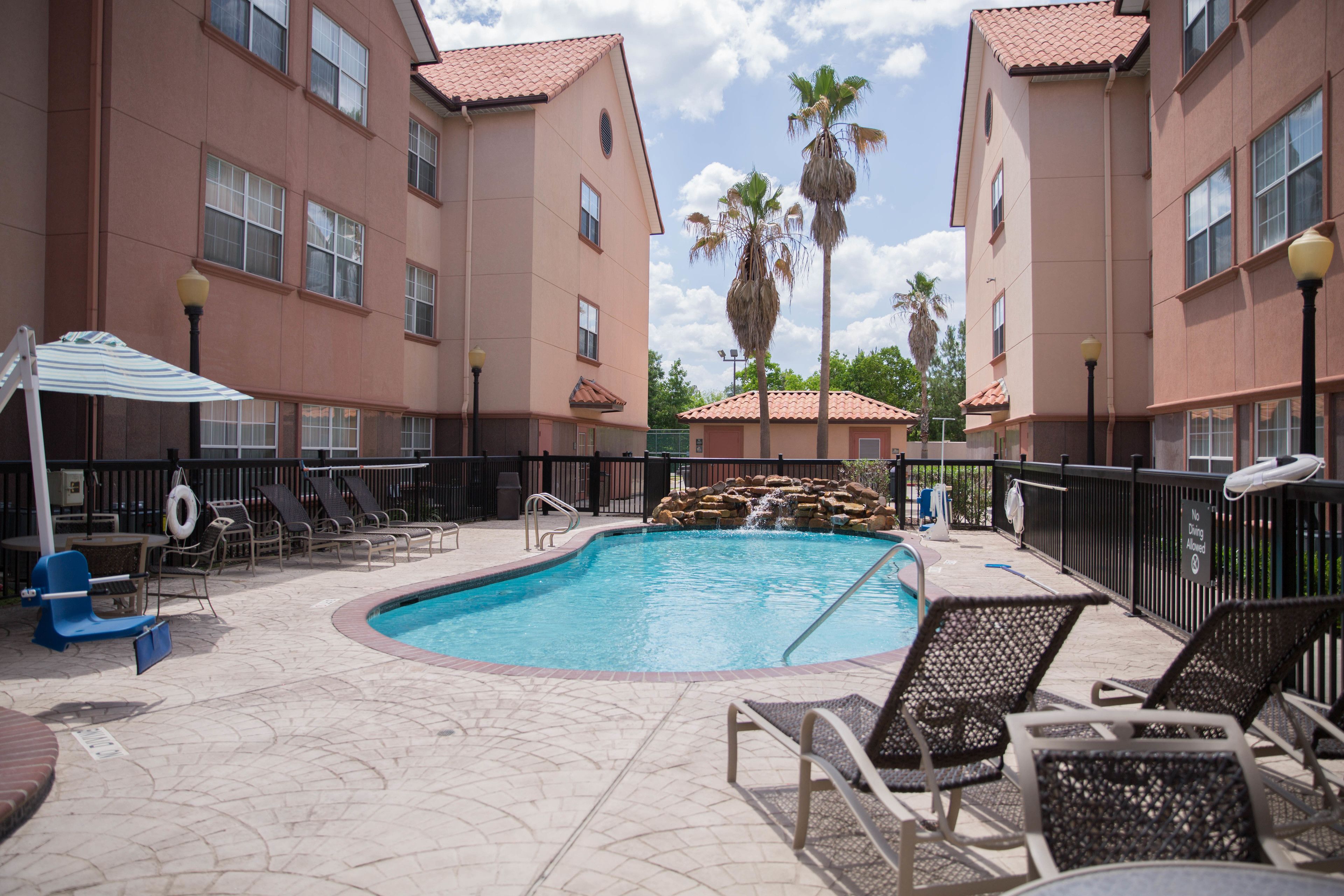 A swimming pool with lounge chairs and a small waterfall feature.