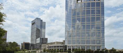 A modern urban landscape with a large body of water, a bridge, and high-rise buildings with reflective glass facades.