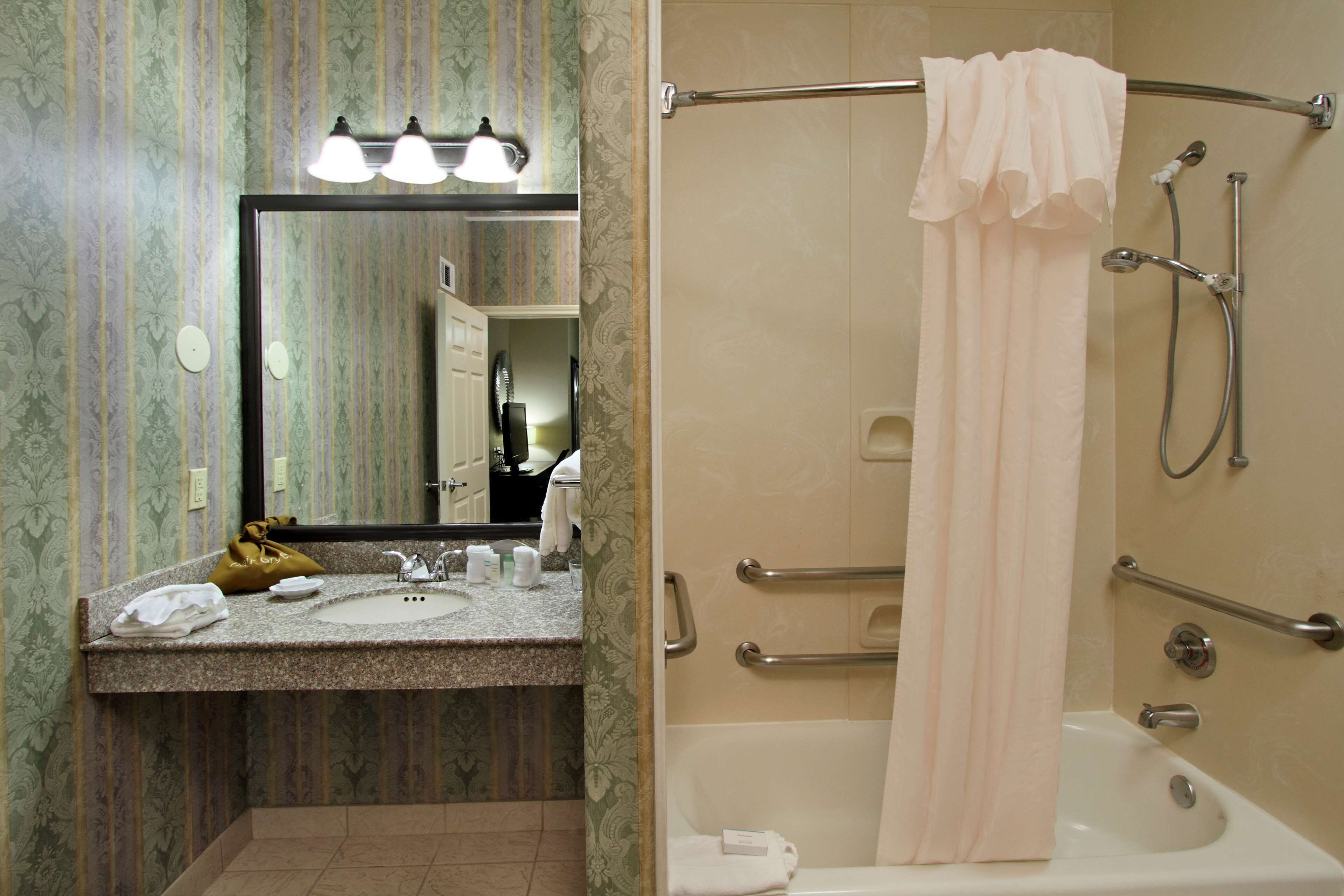 A bathroom with a vanity, sink, mirror, and shower.