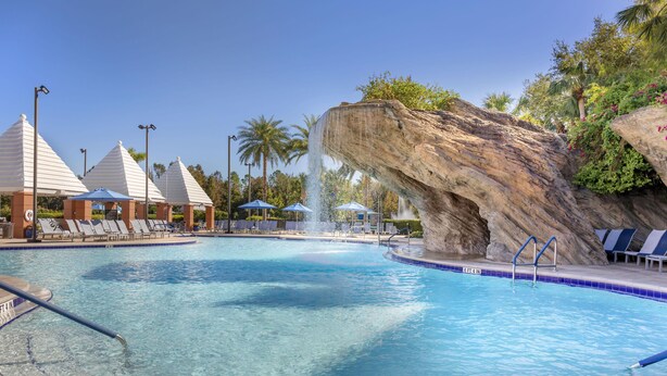 Una piscina con sillas de descanso y una cascada.