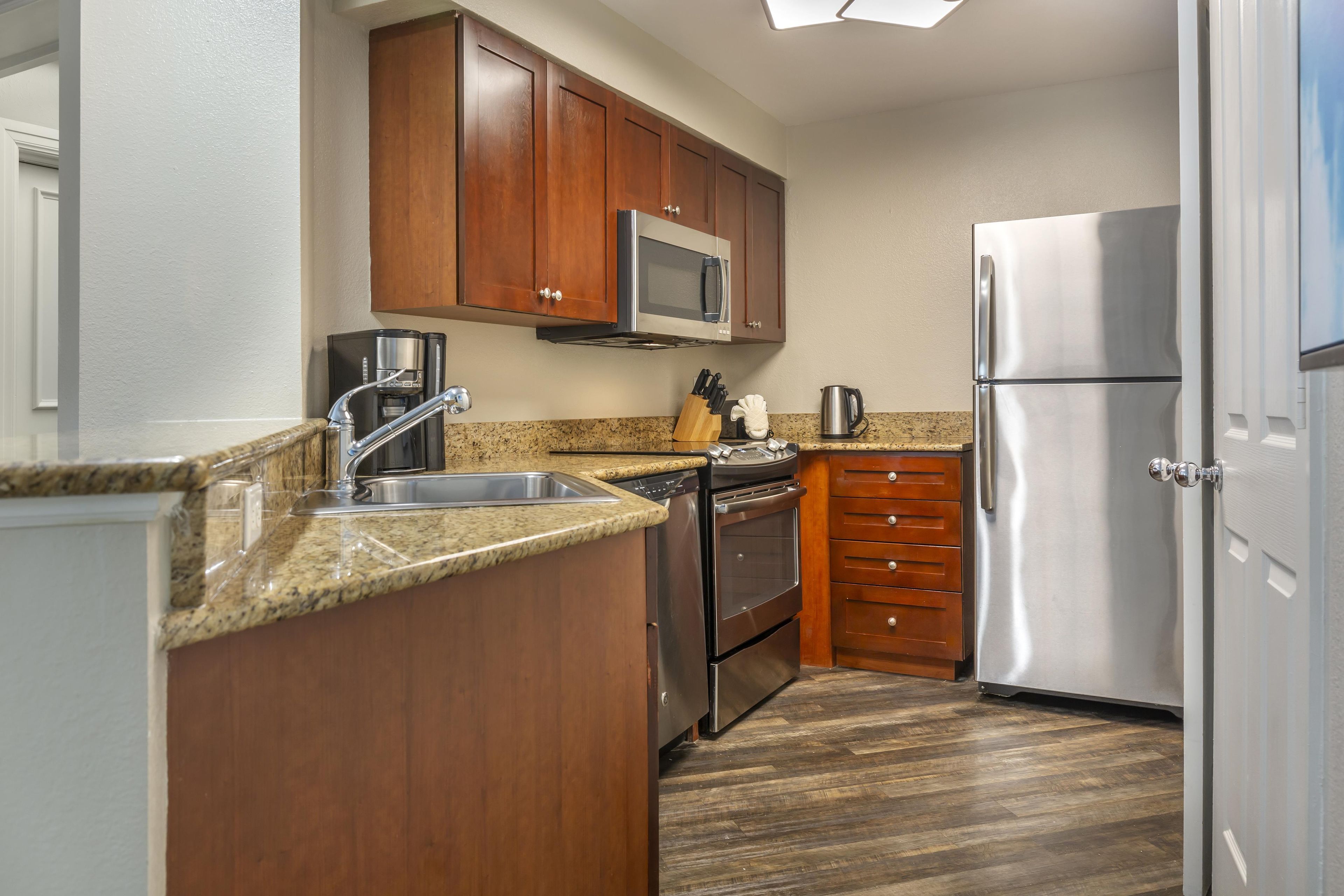 A kitchen with wooden cabinets, stainless steel appliances, and a granite countertop.