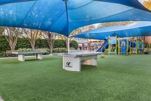 A playground with a blue canopy, artificial grass, and a table tennis table. - Hilton Grand Vacations Club SeaWorld® Orlando (Orlando)
