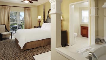 Una habitación de hotel con cama, una silla, una mesa, balcón y baño.