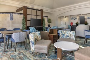 Un vestíbulo de hotel con arreglos de asientos, un televisor de pantalla plana y una pared decorativa con motivos de peces.