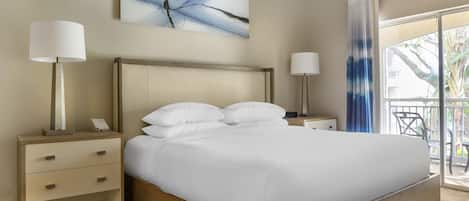 Habitación de hotel con una cama grande, dos mesitas de noche, un teléfono montado en la pared y una ventana con vistas al exterior.