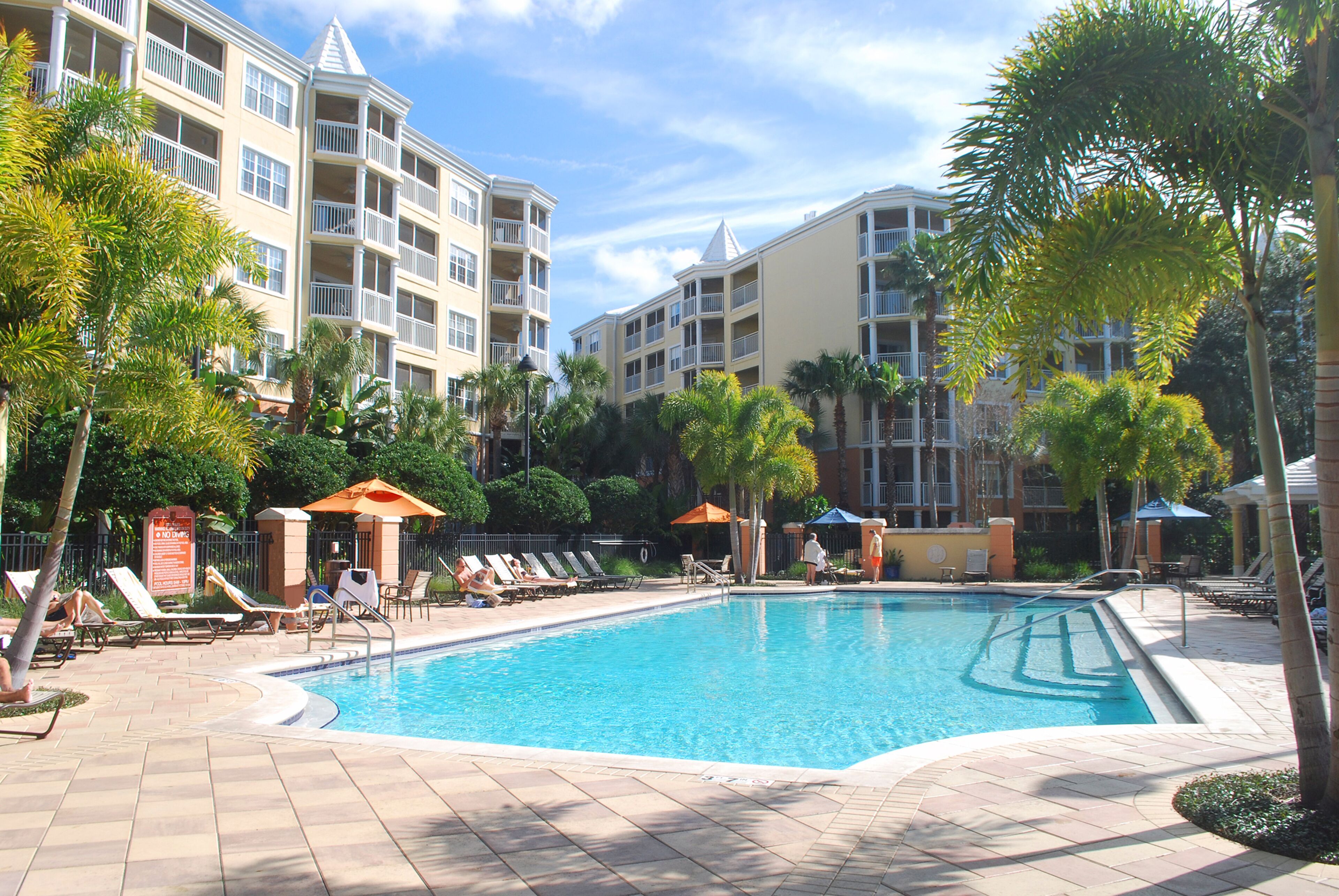 A hotel pool area with sun loungers, umbrellas, and a clear blue pool.