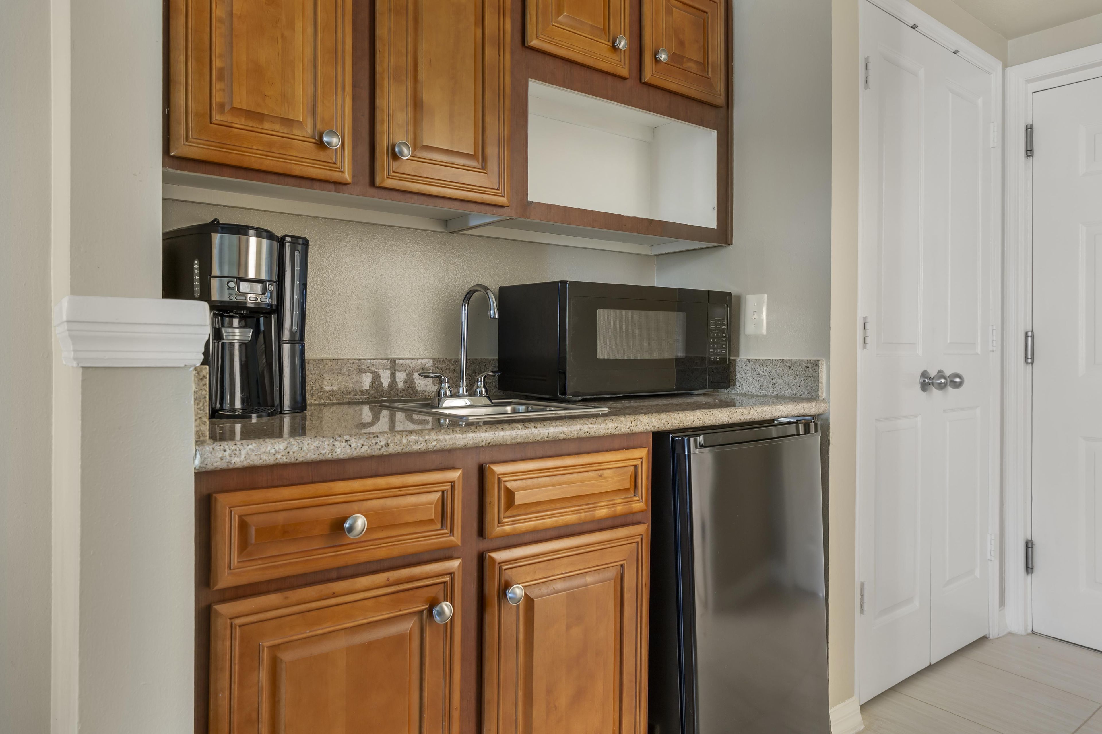 A kitchen with wooden cabinets, a stainless steel dishwasher, a black microwave, and a coffee maker.