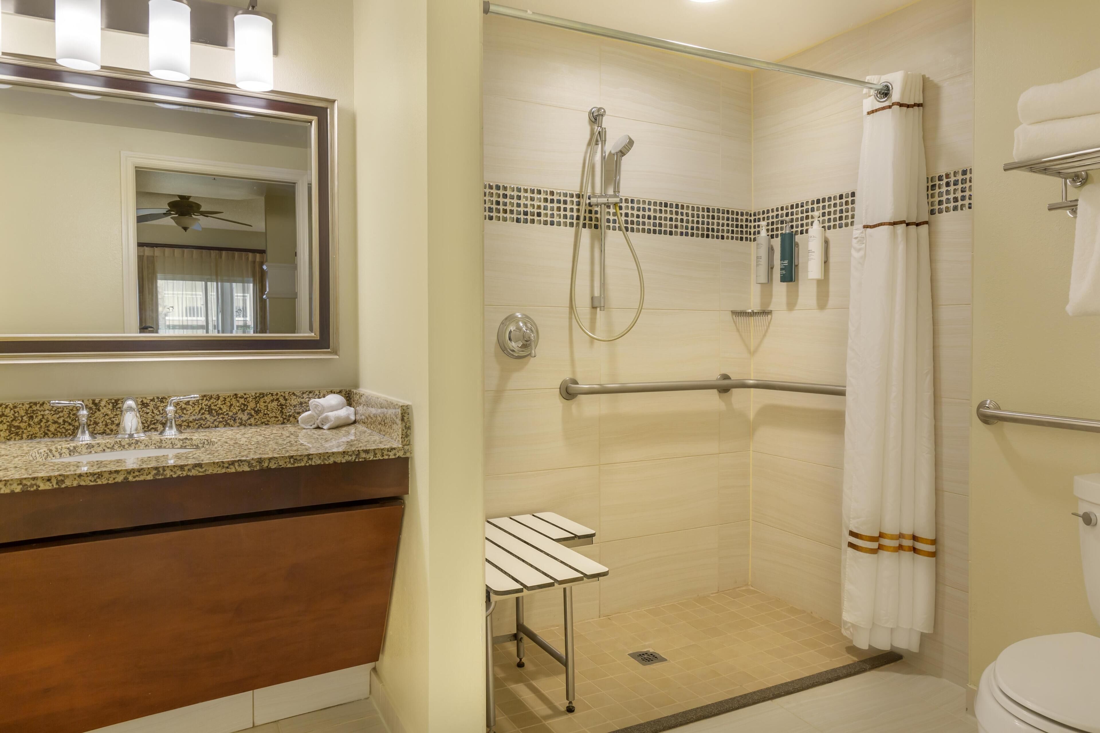 Un baño con cabina de ducha de vidrio, tocador con espejo e inodoro.